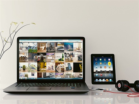 Latop and tablet sitting on top of a desk with headphones attcahed