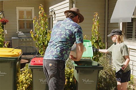 Adult and child pouring organics into bin from caddy